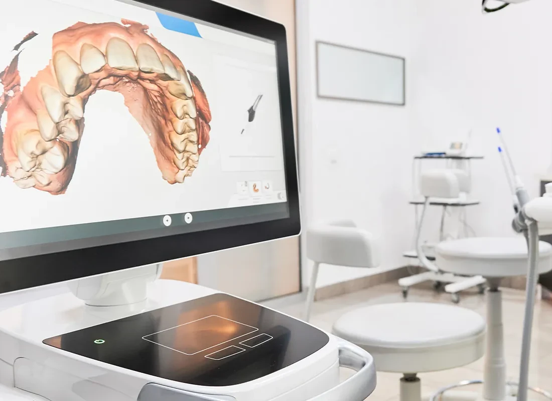 A treatment room with a digital scan of a patient's teeth on the monitor