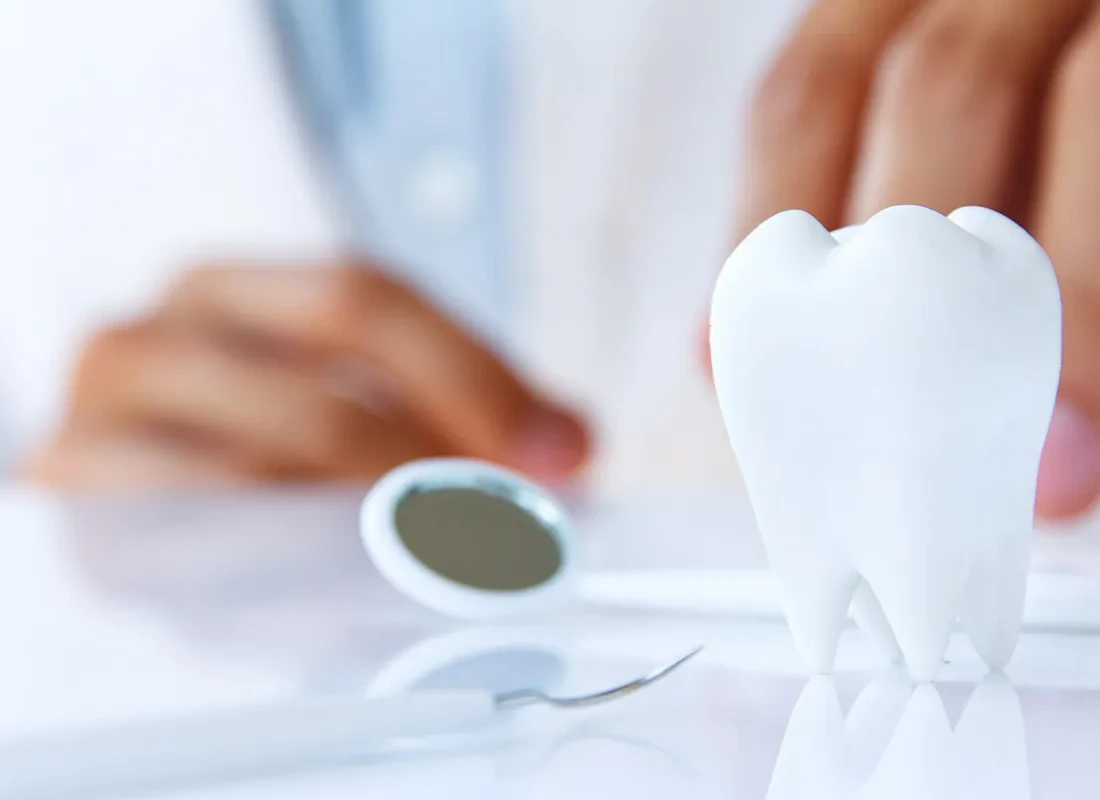 A model tooth and dental mirror on a clinician's desk